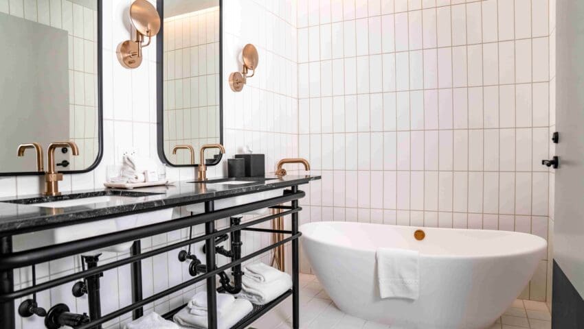 Bathroom with two mirrors hanging just above the sinks and a bathtub lying in the corner