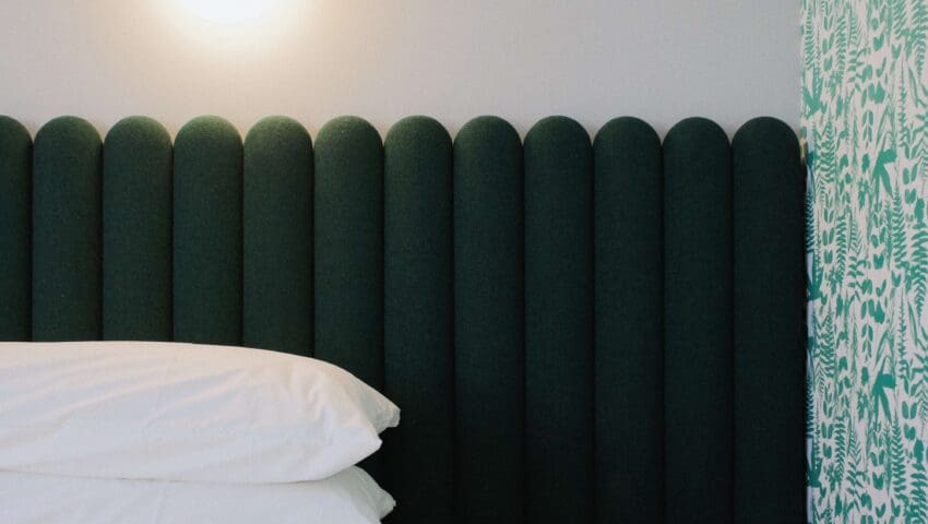 Spongy bed with dark green frame and a small table lying just beside the bed